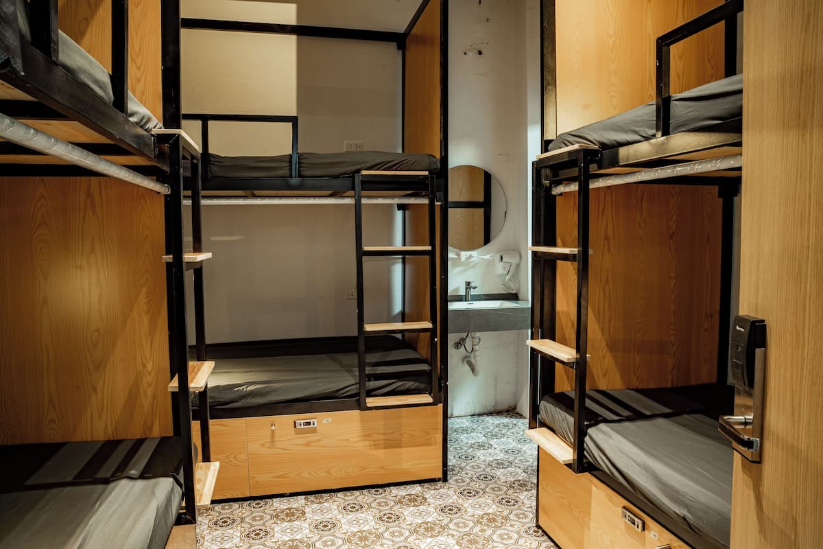 A compact room with bunk beds, a small wooden desk, and a bathroom with a sink.