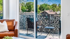 A balcony with a view of mountains, a brown leather sofa, and a small table. - Sugarhouse! Mountain View 3BR, 2BA Gym, Parking (Salt Lake City)