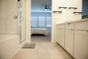 A modern bathroom with a glass shower enclosure, a white bathtub, and a walk-in shower. - Walk On Water Street - Townhouse in historic downtown Henderson (Henderson)