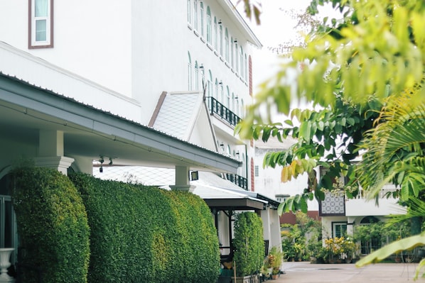 A white building with a covered porch and a balcony. - Aba Village hotel (Chiang Mai)