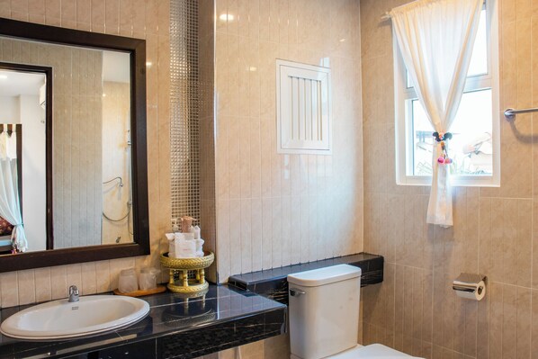 Un baño con lavamanos, inodoro y ventana con cortinas.