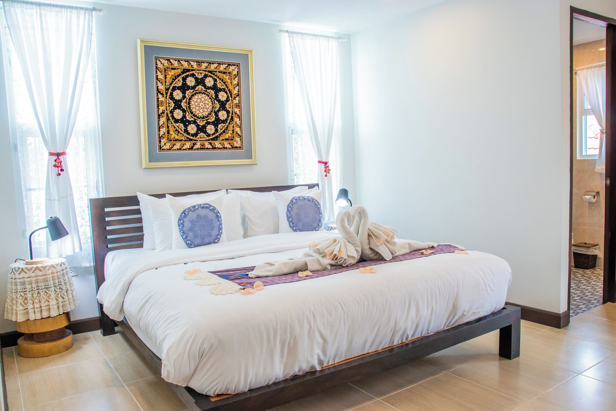 A neatly made bed with a decorative pillow, a wall-mounted artwork, and a bedside lamp.