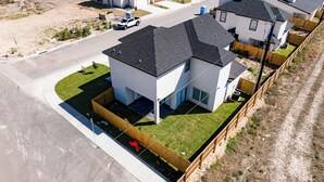 A modern residential area with houses featuring dark roofs and white exteriors, surrounded by a wooden fence and a well-maintained lawn. - GREAT LOCATION  Beautiful 2-bedroom house in Mission (Mission)