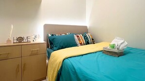 Quarto com cama, mesa de cabeceira, cômoda e ar-condicionado fixado na parede.