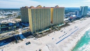 Ein Hochhaus-Hotel mit mehreren Stockwerken, einer Lage am Strand und einem sichtbaren Poolbereich.