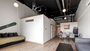 A modern, well-lit room with a bed, a sofa, a dining area, and a kitchenette. - Central Lofts Unit 1 (Queenstown)