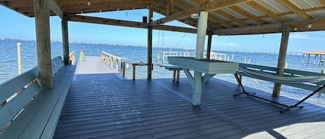 A wooden pier with benches and a picnic table, overlooking a body of water.