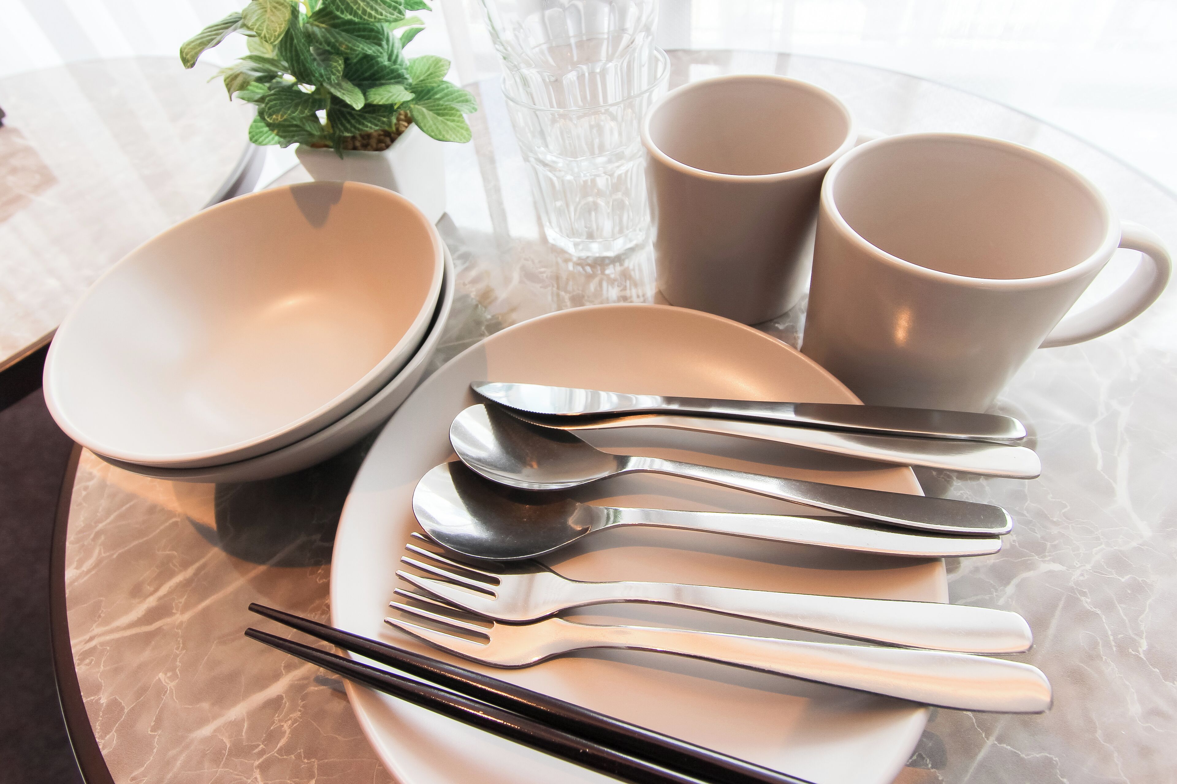 Une table dressée avec des assiettes, des bols, des tasses et des couverts.