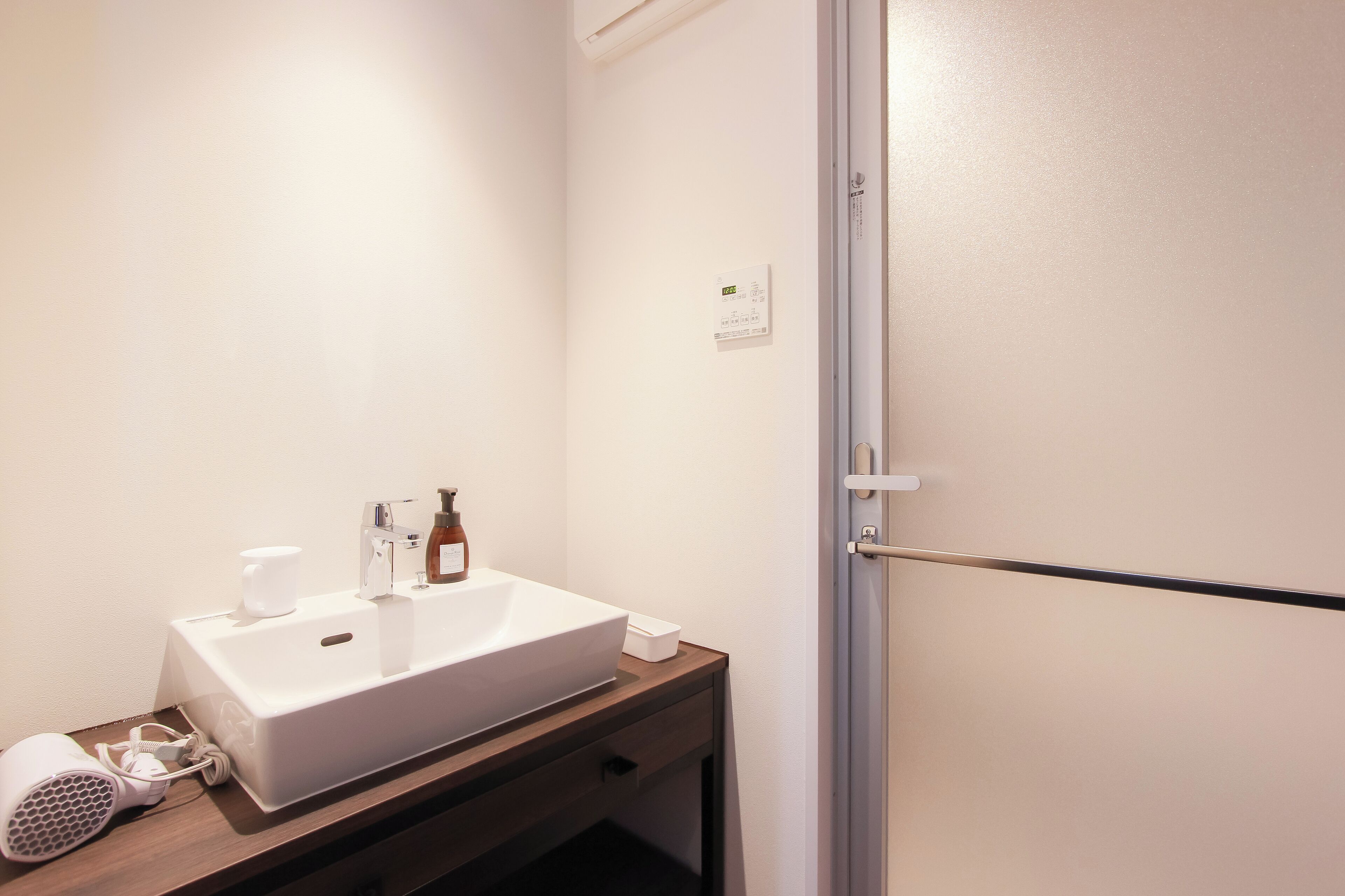 Een badkamer met een witte wastafel, een haardroger en een fles shampoo.