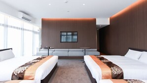 Una habitación de hotel moderna con dos camas, un sofá, una mesita y un ventanal grande.
