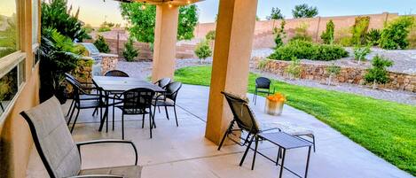 A covered patio area with a table and chairs, a ceiling fan, and string lights.