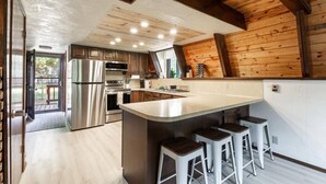 Una cocina moderna con electrodomésticos de acero inoxidable, vigas de madera y una isla grande con taburetes de bar.