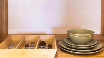 Un organizador de cajones de madera con utensilios y platos apilados.