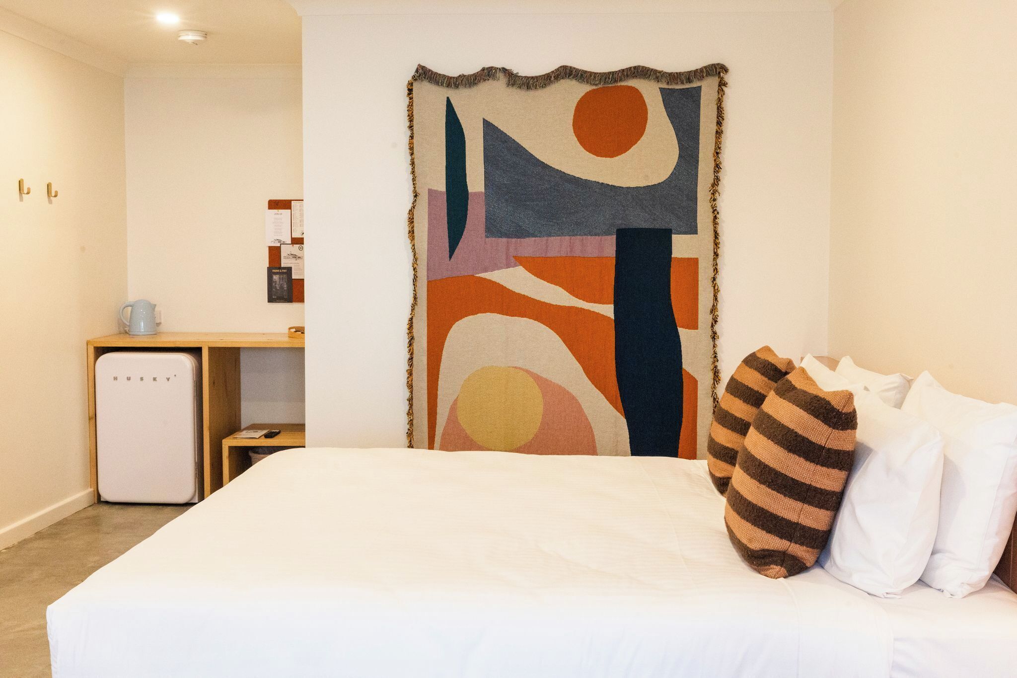 A hotel room with a bed, a desk, and a refrigerator.