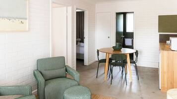 A compact living space with a dining area, a green patterned sofa, and a kitchen counter.