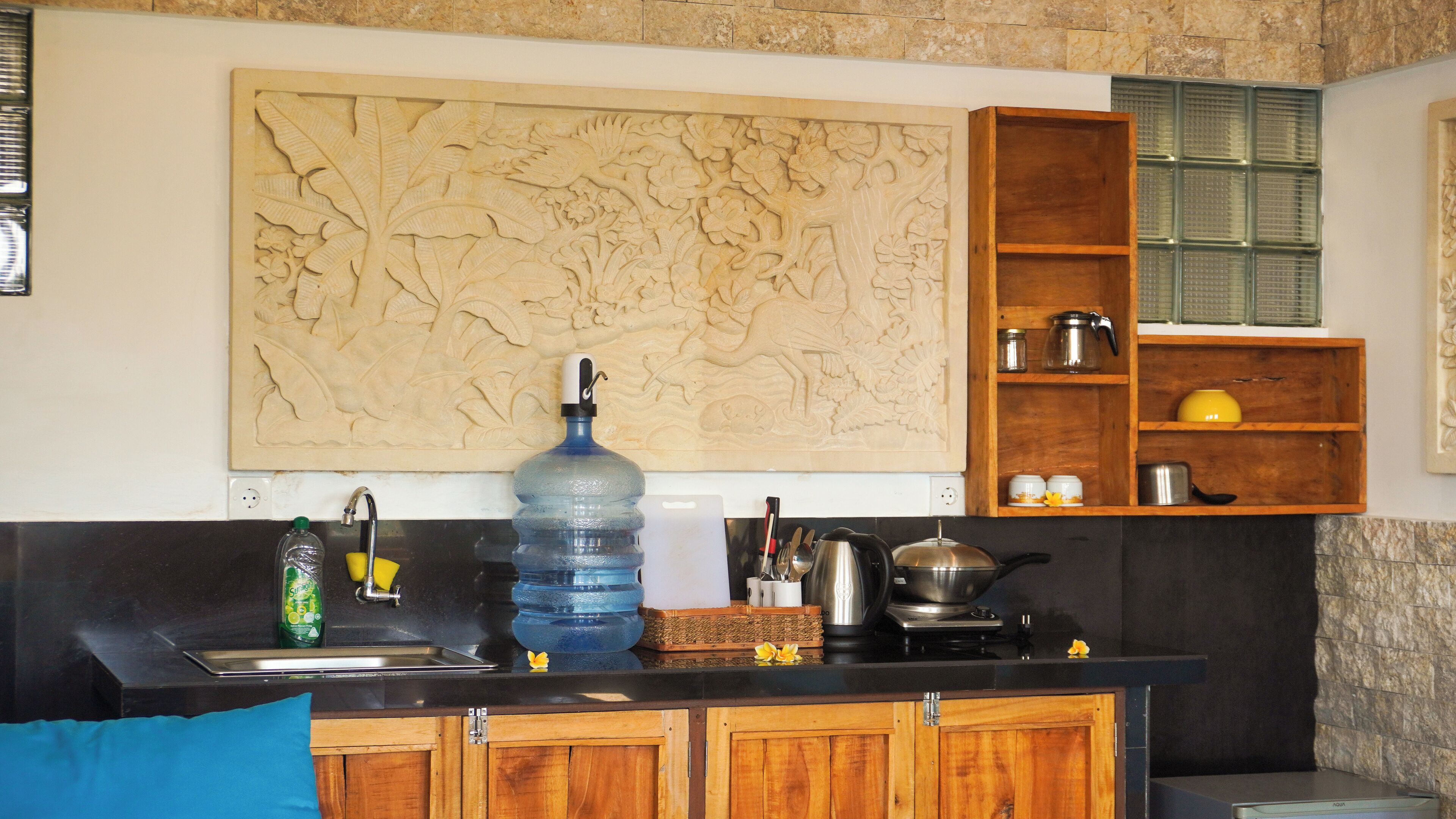 Una cocina con un gran relieve tallado en la pared, un dispensador de agua y armarios de madera.