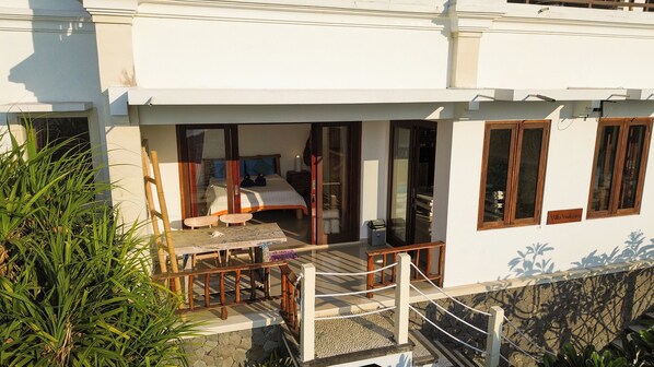 A bedroom with a bed, a nightstand, and a window. - Kalimaja Amed Villa (Karangasem)