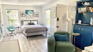A modern bedroom with a bed, a desk, a chair, and a bookshelf.