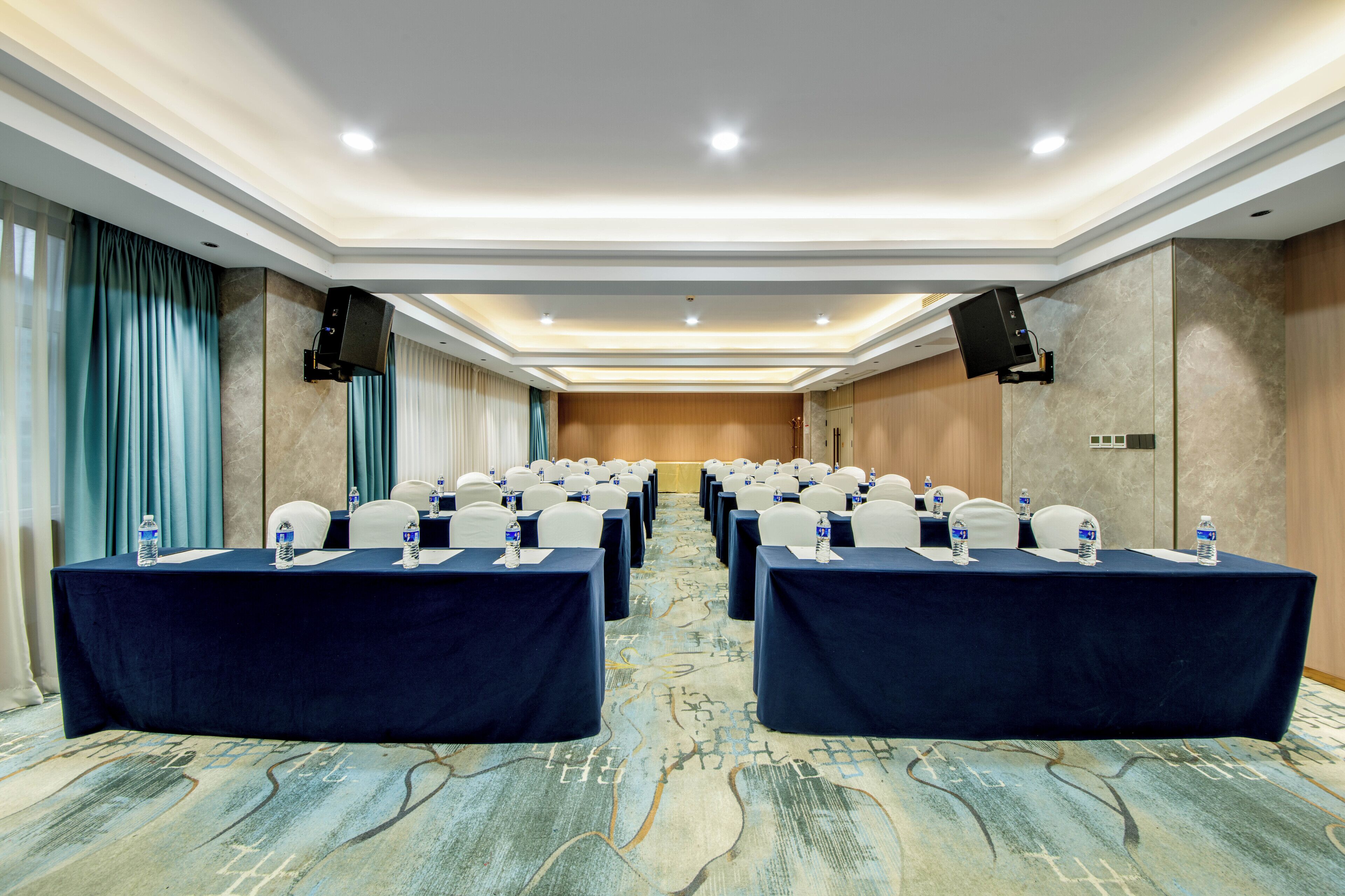 Un salón de conferencias con mesas, sillas y un escenario.
