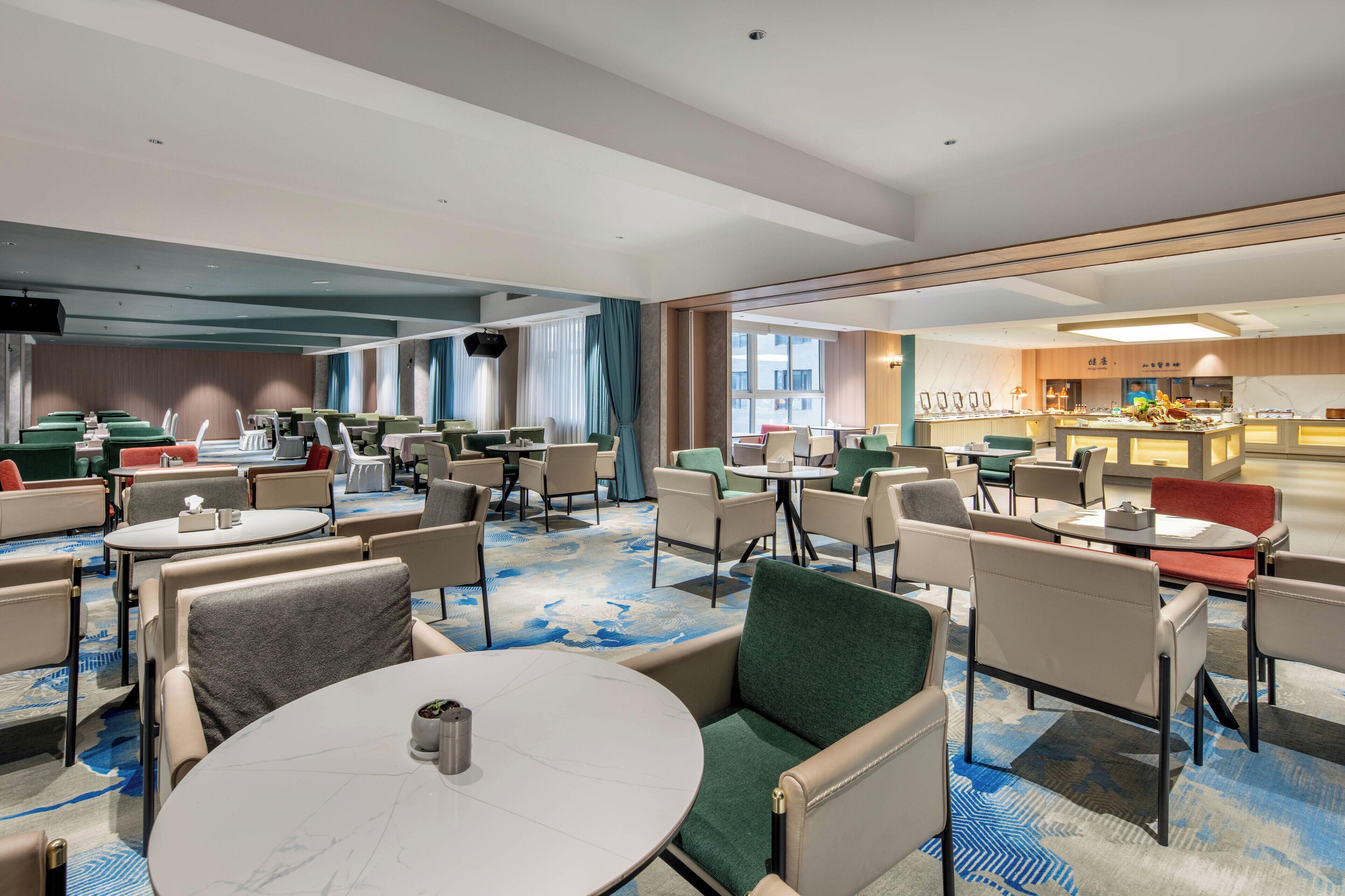 A hotel lobby with multiple seating areas, a bar, and a view of the cityscape.