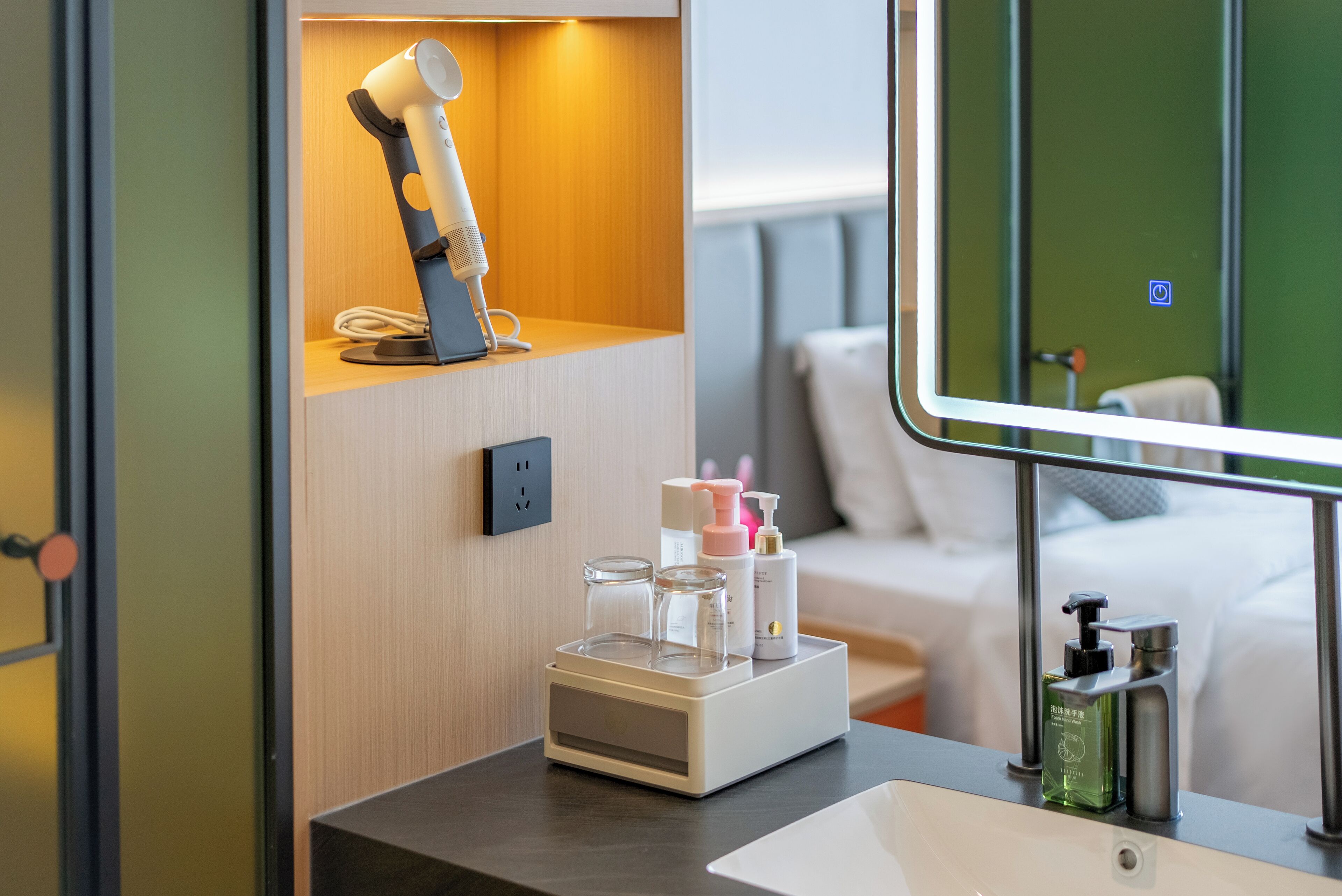 A hotel bathroom with a sink, mirror, and toiletries.