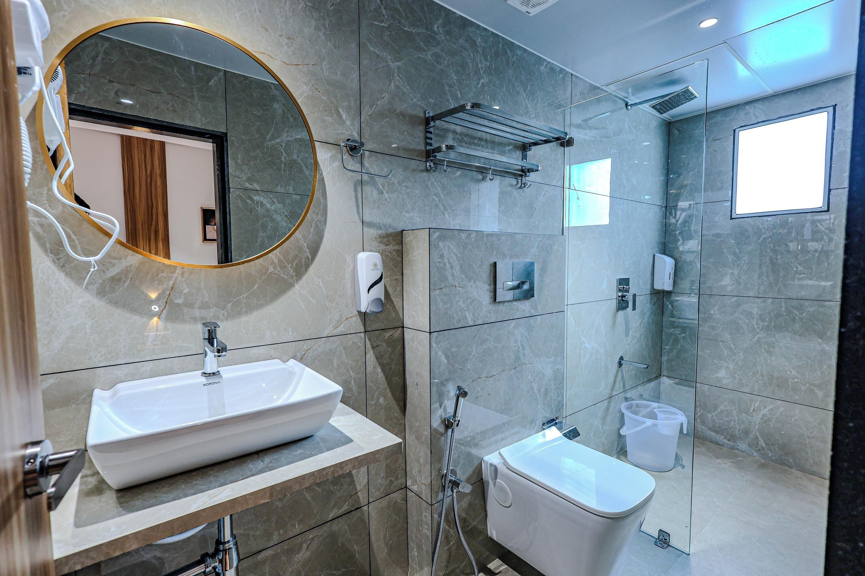 Un baño moderno con un espejo grande, un lavamanos, un inodoro y una zona de ducha.
