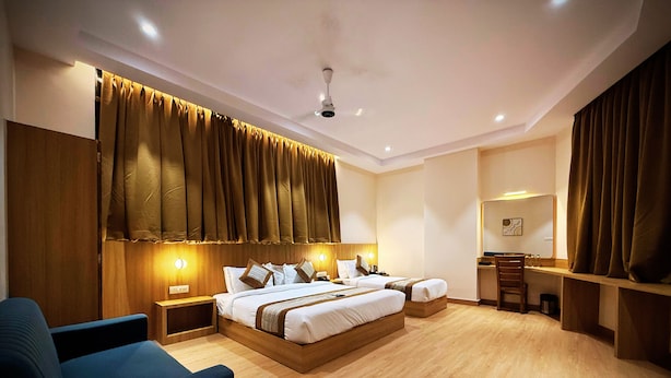 A modern hotel room with a large bed, bedside tables, a desk, and a chair. - Hotel Alfa Suites (Mumbai)