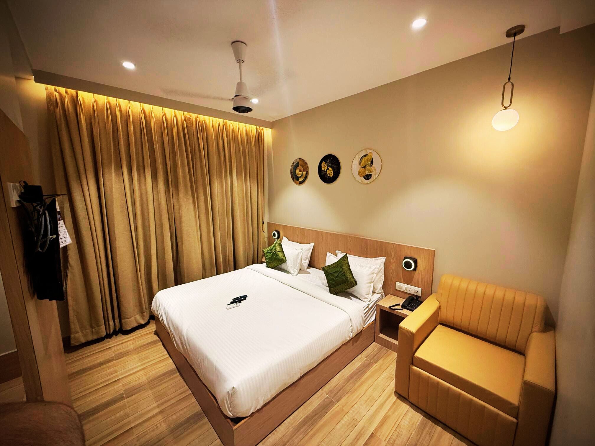 Ein Hotelzimmer mit einem großen Bett, einem Nachttisch, einem Sessel, einem Deckenventilator und einer Wandleuchte.