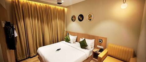 Ein Hotelzimmer mit einem großen Bett, einem Nachttisch, einem Sessel, einem Deckenventilator und einer Wandleuchte.