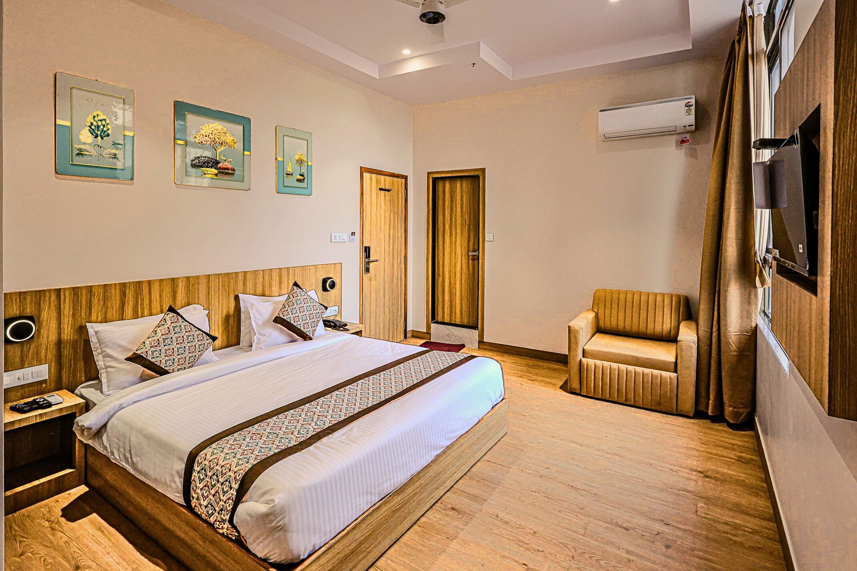 Une chambre d’hôtel avec un grand lit, un canapé, une télévision et un appareil de climatisation.