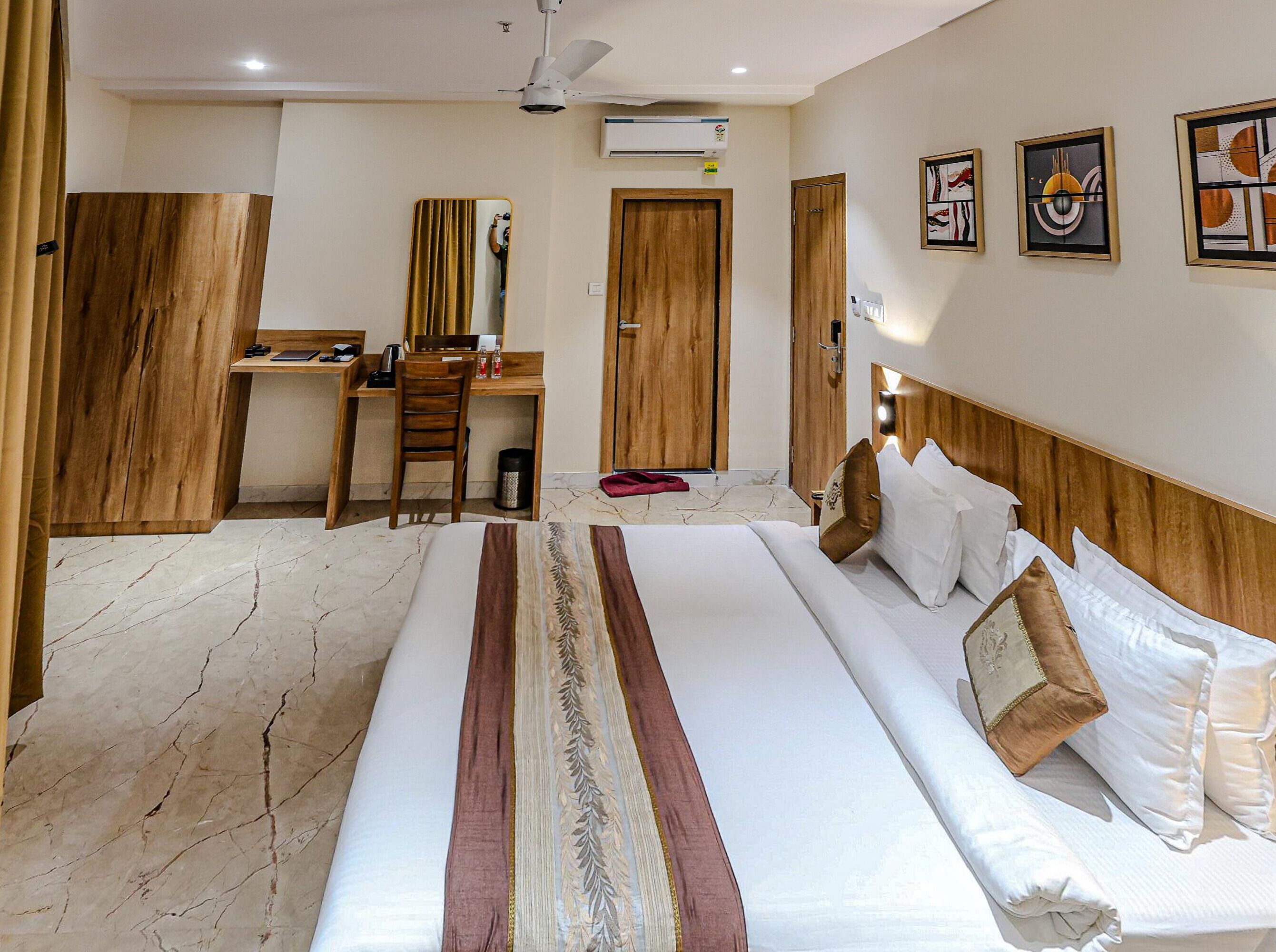 A hotel room with a bed, a desk, a chair, a wardrobe, and a mirror.