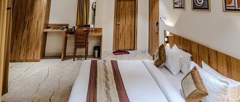 A hotel room with a bed, a desk, a chair, a wardrobe, and a mirror.