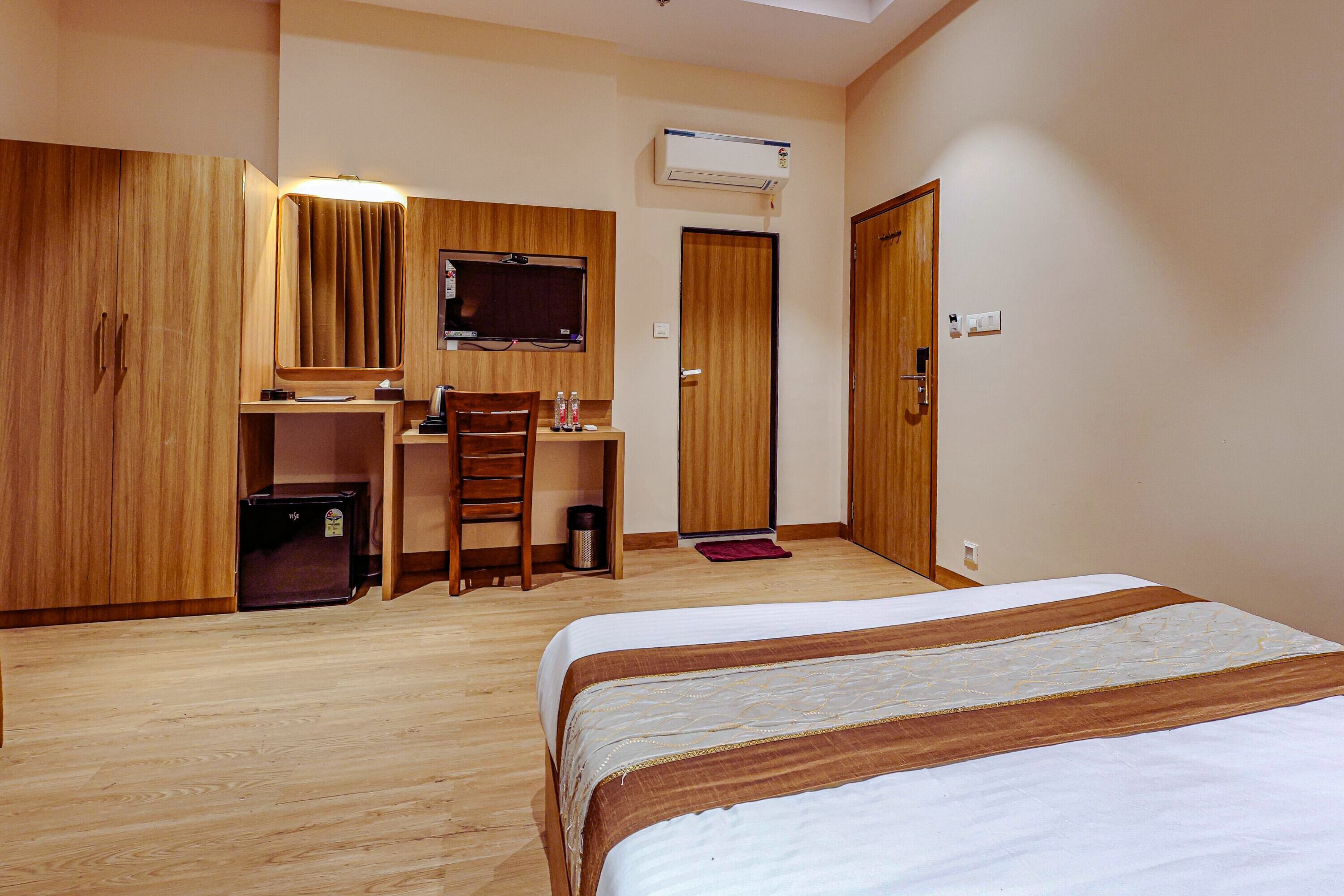 Una camera d'albergo con un letto, una scrivania con sedia, una televisione e un armadio.