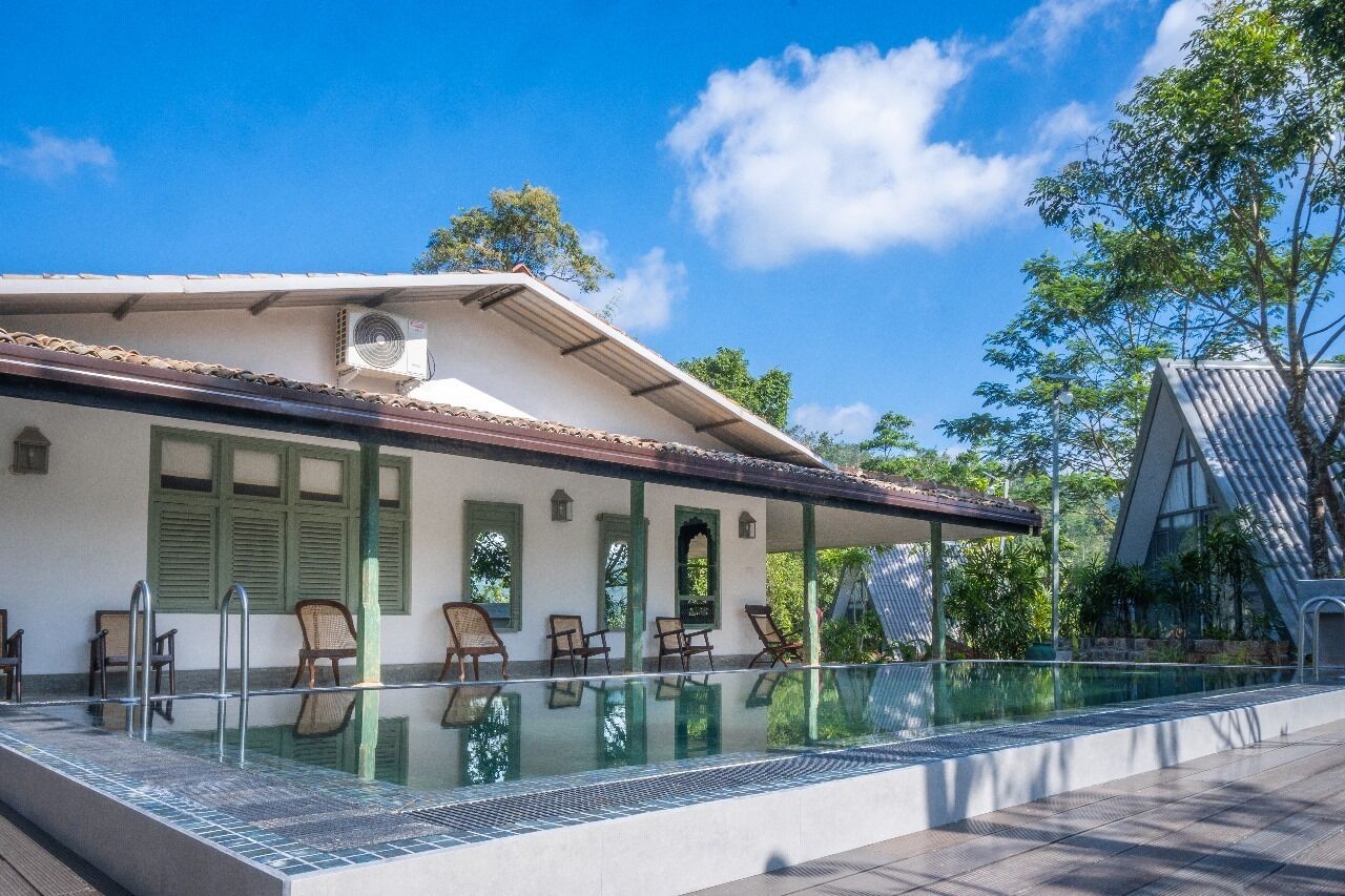 A building with a pool, green shutters, and outdoor seating.