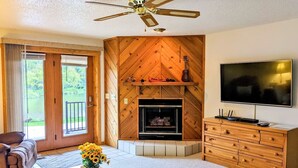 Una sala de estar con chimenea, paredes de madera, televisor y un sofá.