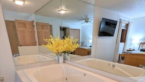 Un baño moderno con una bañera independiente grande, un espejo y un florero con flores amarillas.