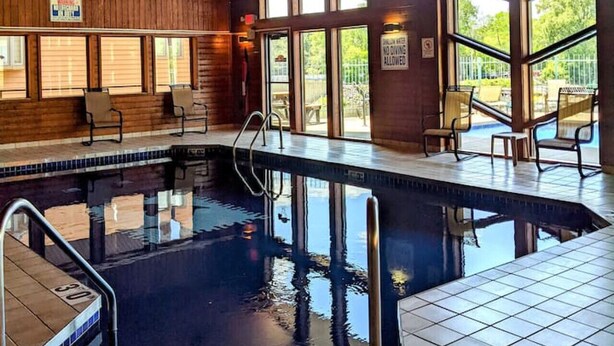 Una piscina interior con techo de madera y ventanas amplias.