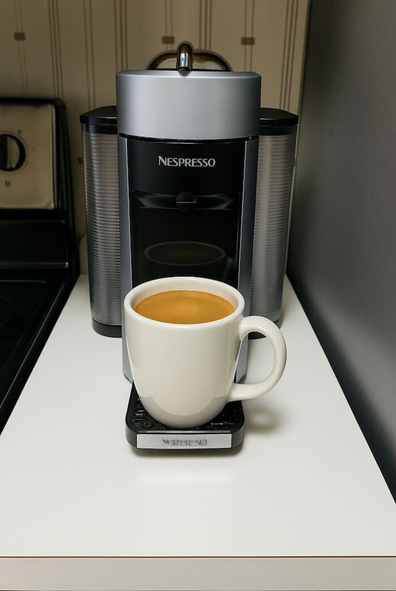 A Nespresso coffee machine with a cup of coffee on a white countertop.
