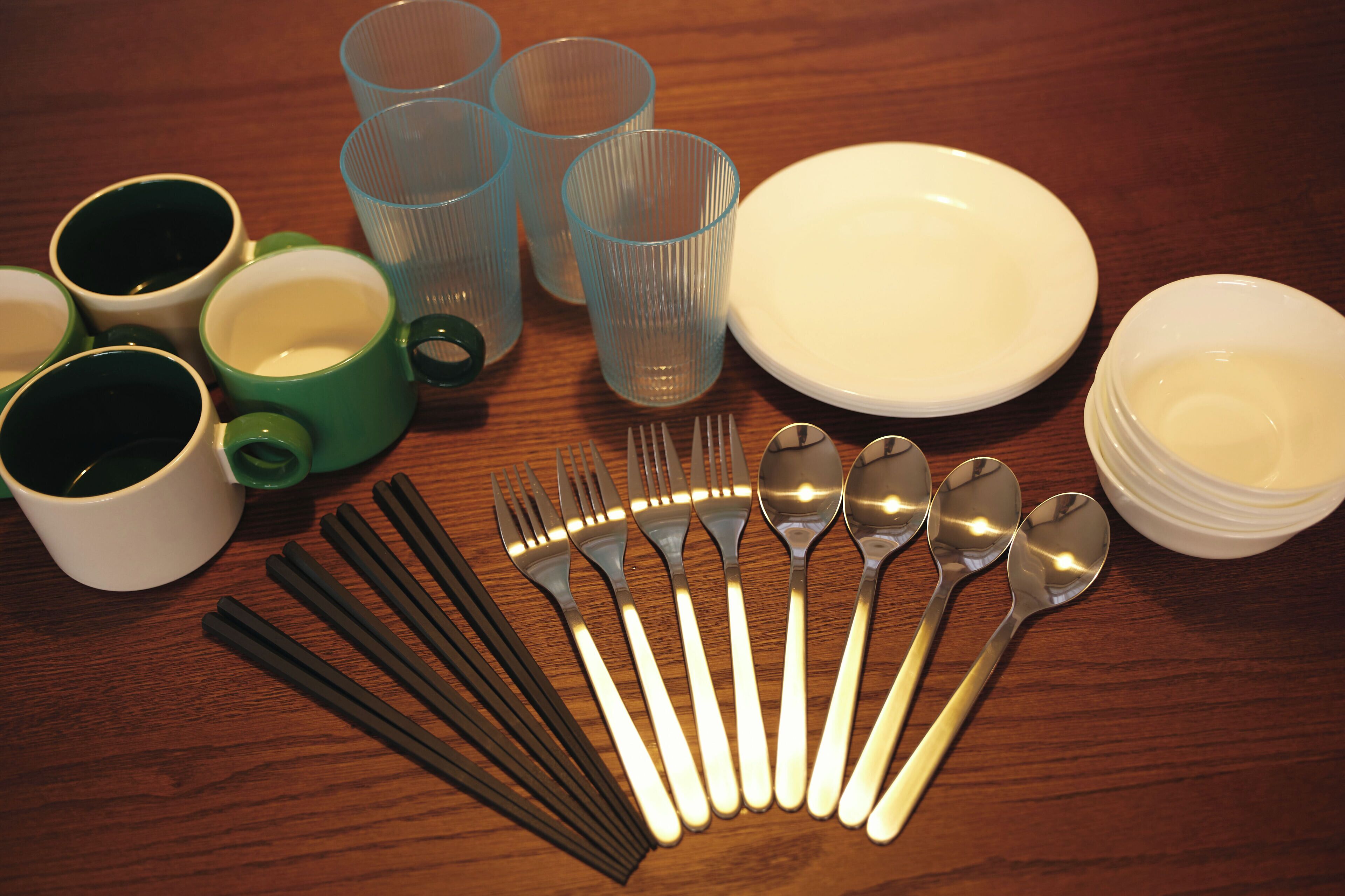 A table set with clear drinking glasses, a white plate, a white bowl, and a set of silverware.