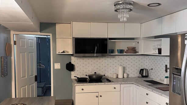 A modern kitchen with white cabinets, a stainless steel refrigerator, and a chandelier. - Zenbnb Lansdowne escape, with secure parking spot (Lansdowne)