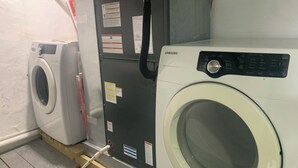 A laundry room with two washing machines, one white and one black, and a utility meter. - Zenbnb Lansdowne escape, with secure parking spot (Lansdowne)