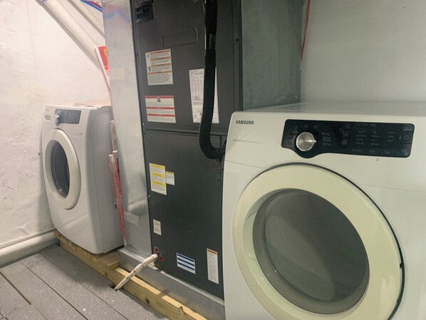A laundry room with two washing machines, one white and one black, and a utility meter.