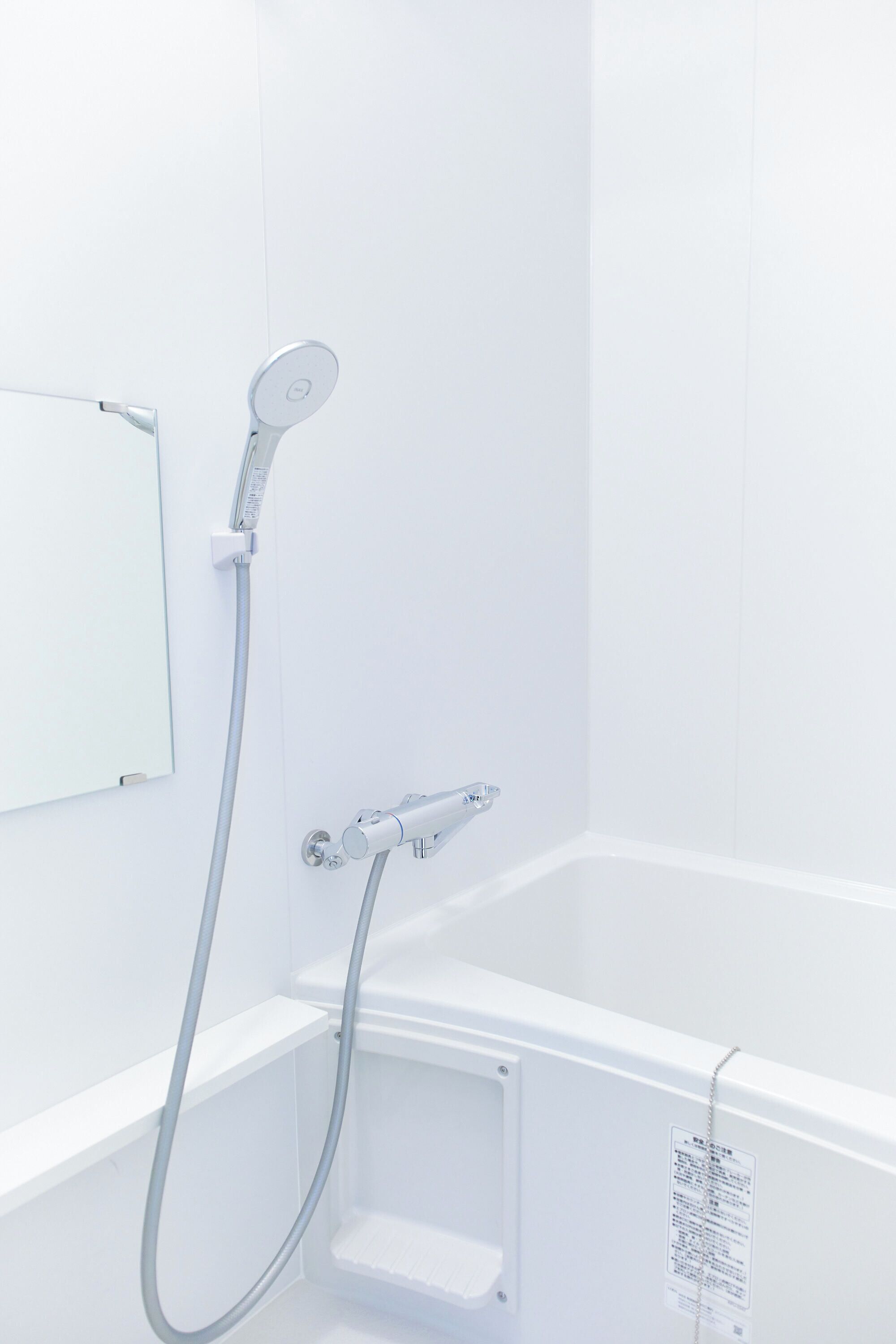 A modern bathroom with a shower, a mirror, and a control panel.