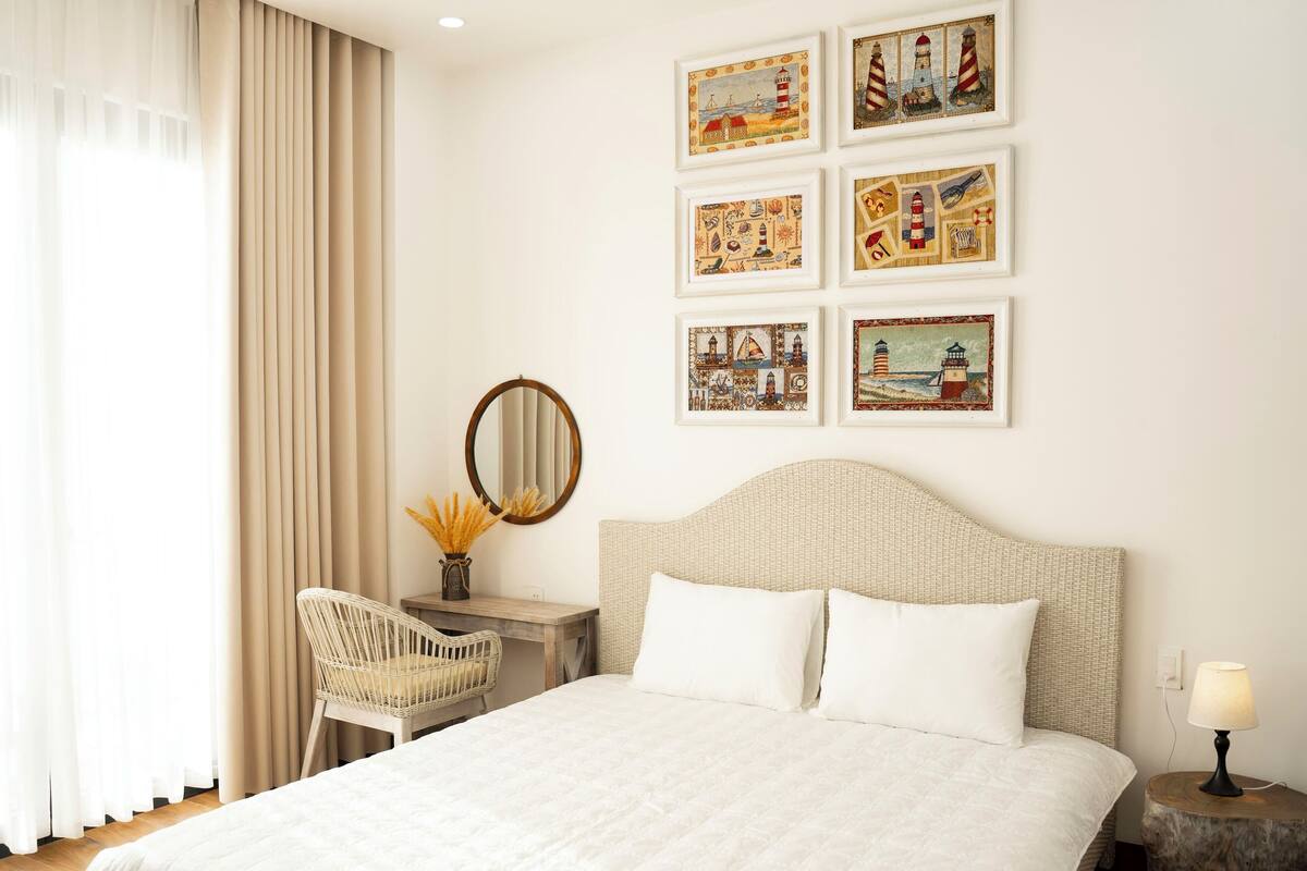 Een hotelkamer met een groot bed, een bureau met stoel, een ronde spiegel en kunst aan de muur.
