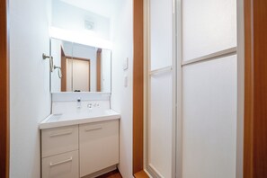 Ein Badezimmer mit einem weißen Waschbecken, einem Spiegel und einer Holztür.