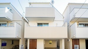 Un immeuble résidentiel de deux étages, doté d’une entrée centrale, d’un petit balcon à l’étage supérieur et d’un vélo garé à l’extérieur.