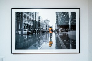 A framed photograph of a person walking on a wet city street with modern buildings. - Tokyo Home Base Haneda (Tokyo)