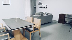 A modern living room with a grey sofa, a dining table with chairs, and a small cabinet. - Modern Apartment in Sydney CBD Heart (Sydney)