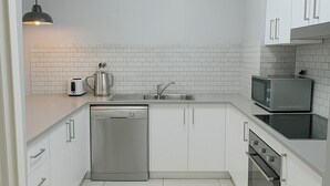 A modern kitchen with white cabinets, a dishwasher, a microwave, and an oven. - Modern Apartment in Sydney CBD Heart (Sydney)