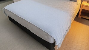 A neatly made bed with a light-colored duvet and pillows, a wooden headboard, and a bedside table with a lamp. - Modern Apartment in Sydney CBD Heart (Sydney)